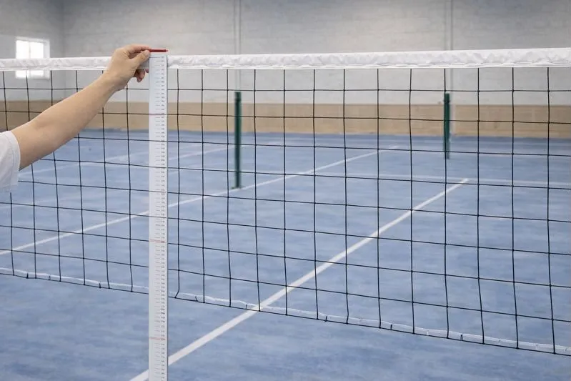 体育館でネット測定スケールを使いバドミントンネット中央の高さ152.4cmを測定しているシーン