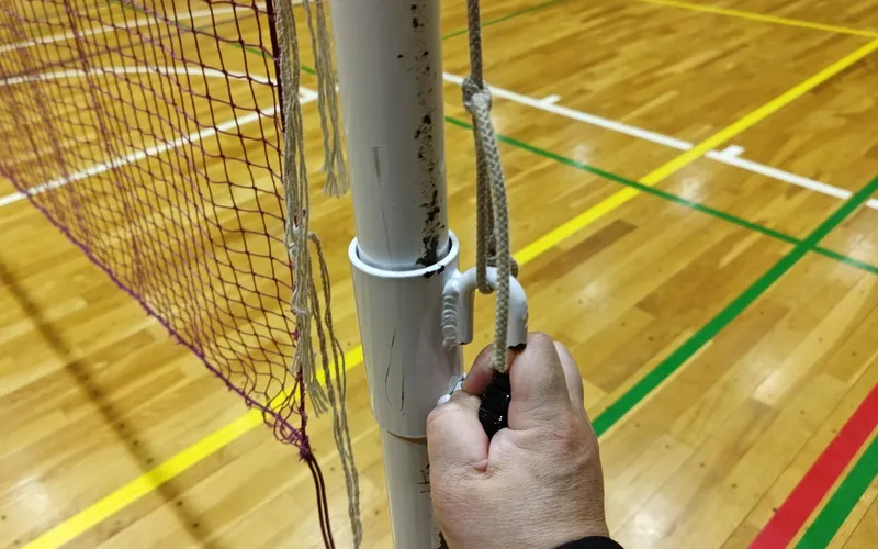 ネットを引きながら固定部品を下げてボルトでロックしている様子