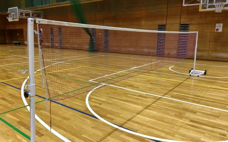 全体を確認しながらバドミントンネット中央のたるみを調整している様子